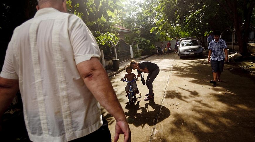 Родной сын и приемная дочь Соренсена играют во дворе возле их дома в Тайланде