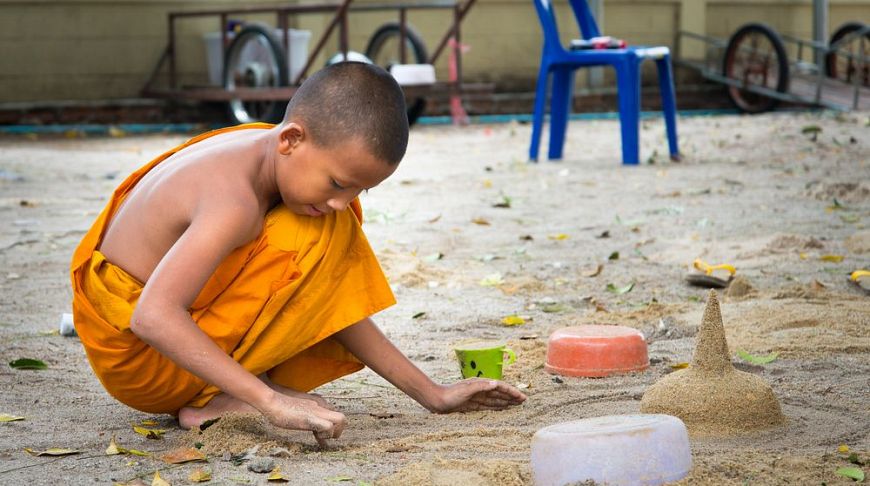 Мальчик-монах играет в песке